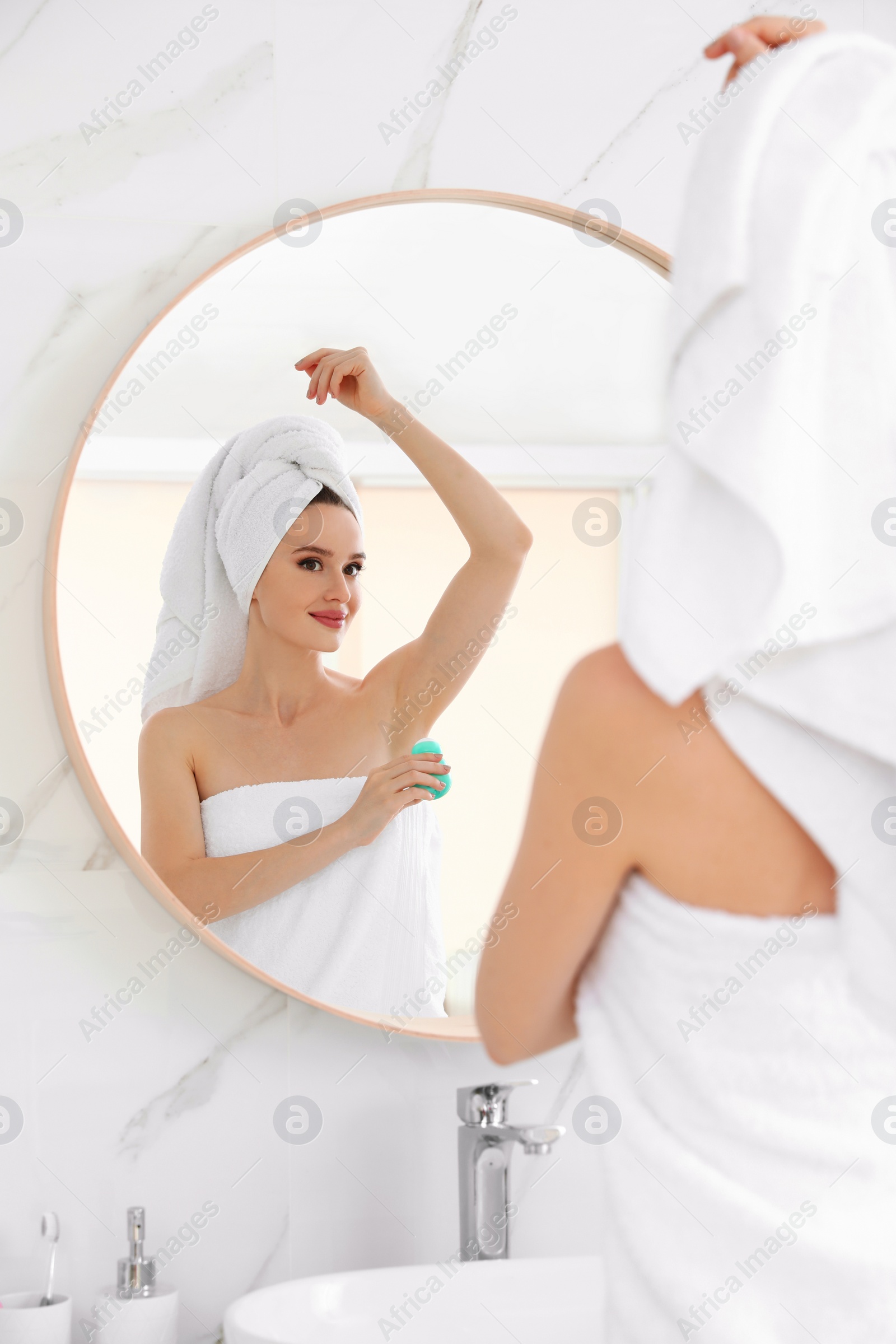 Photo of Beautiful young woman applying deodorant after shower in bathroom