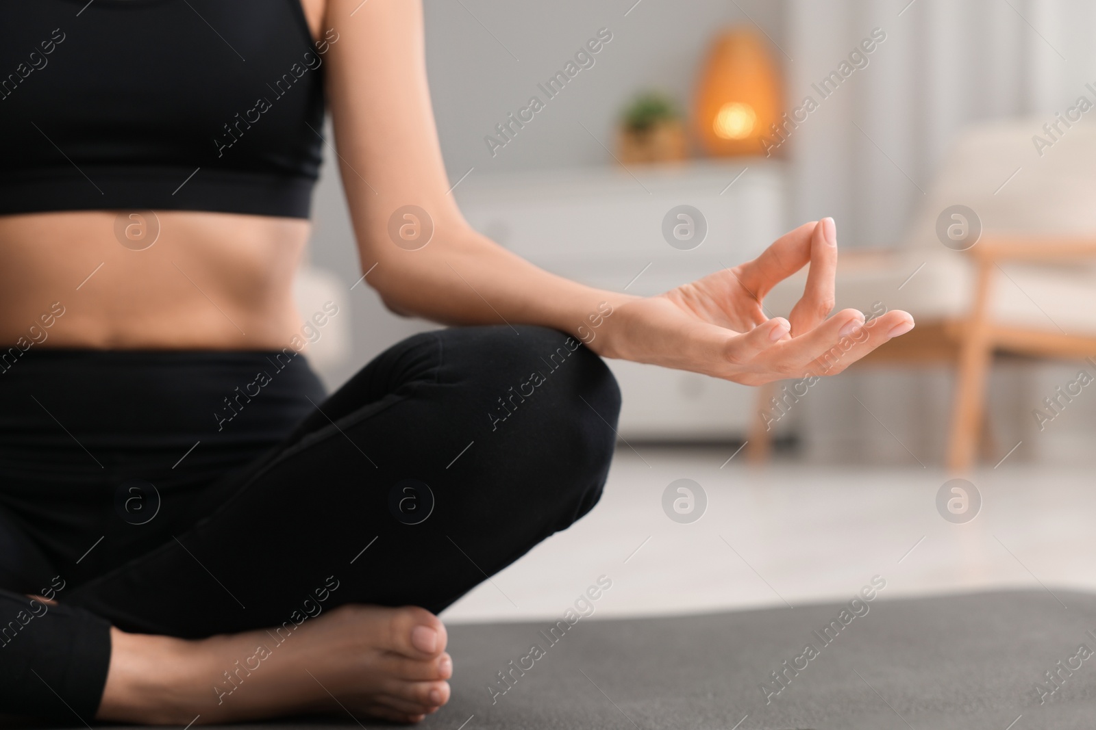 Photo of Woman practicing Padmasana on yoga mat at home, closeup. Lotus pose