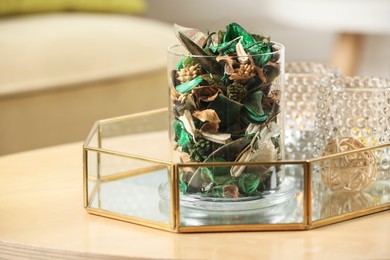 Glass jar with aromatic potpourri of dried flowers and different decor element on wooden table indoors. Space for text