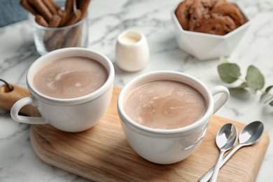 Photo of Cups with hot cocoa drink on table