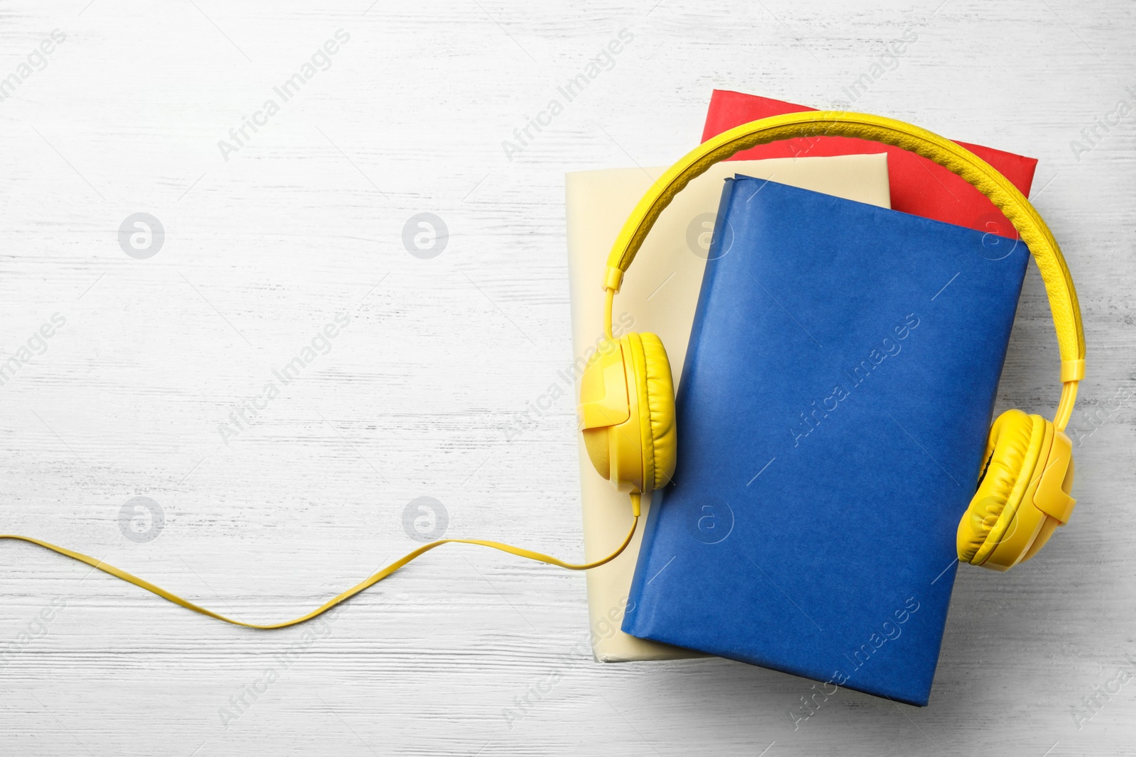 Photo of Books and modern headphones on white wooden table, top view. Space for text