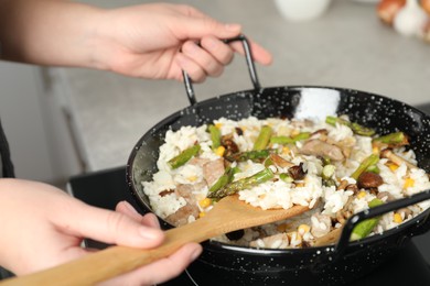 Photo of Woman cooking delicious risotto, closeup. Tasty recipe