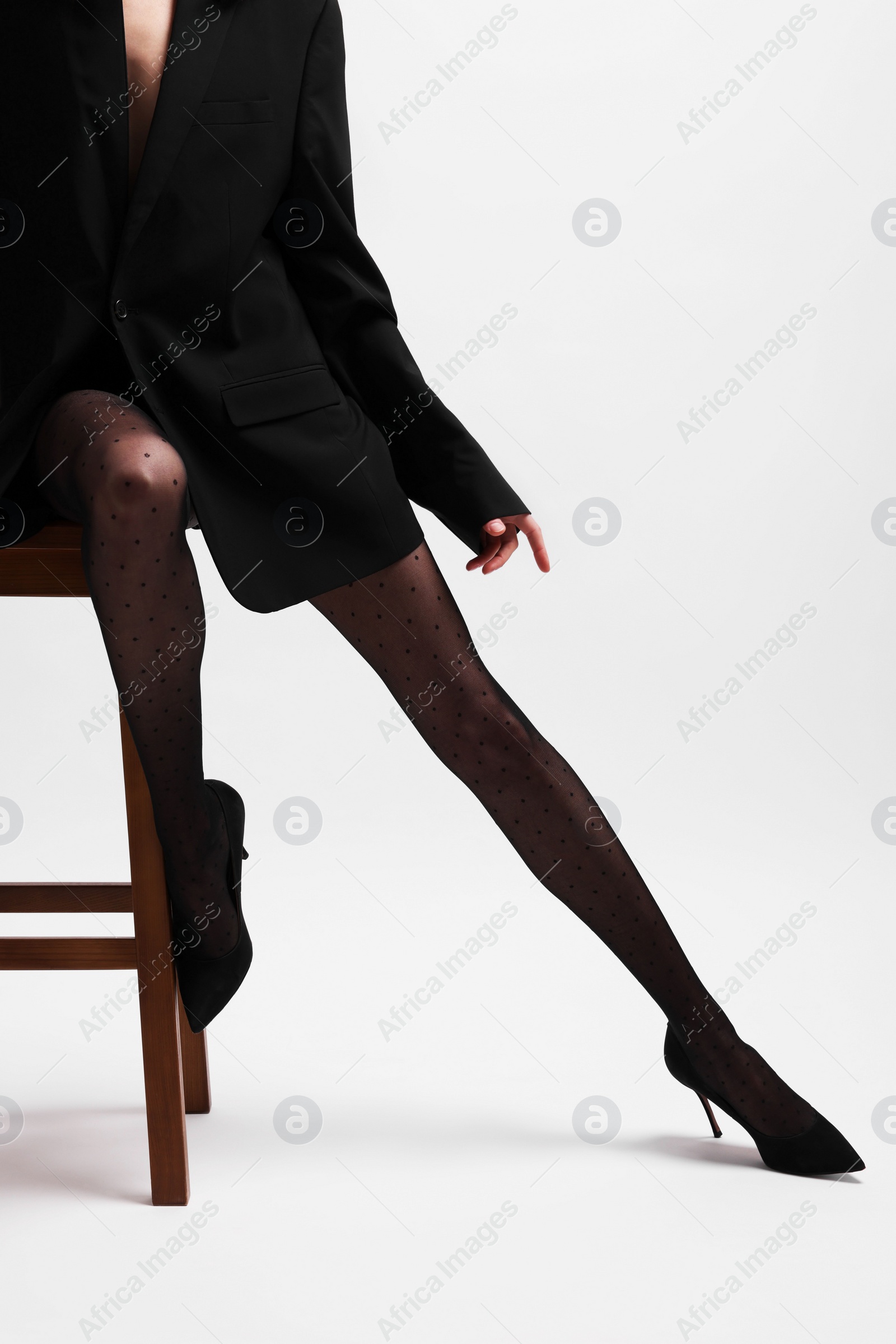 Photo of Beautiful woman in stylish black outfit on stool against white background, closeup