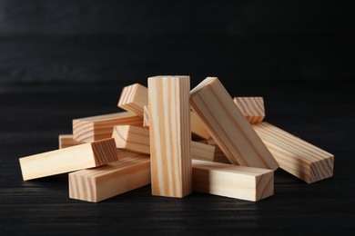 Photo of Pile of wooden blocks on black table. Jenga tower