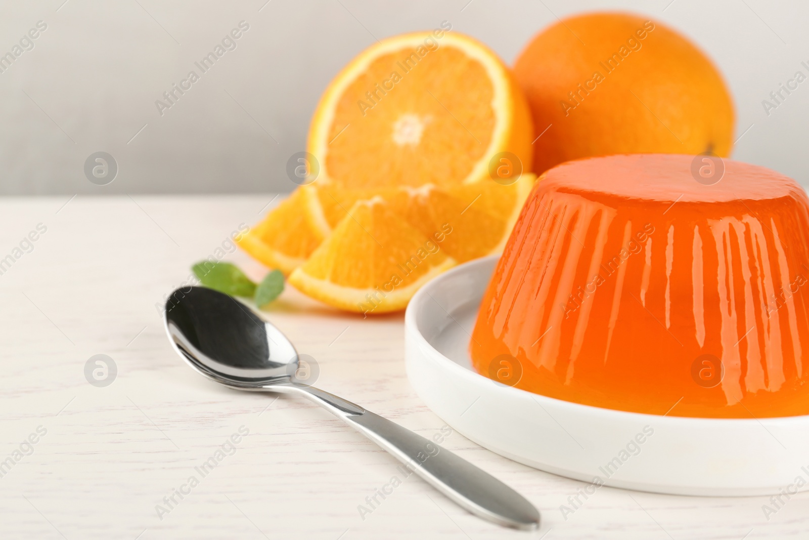 Photo of Plate with tasty orange jelly served on white wooden table, space for text