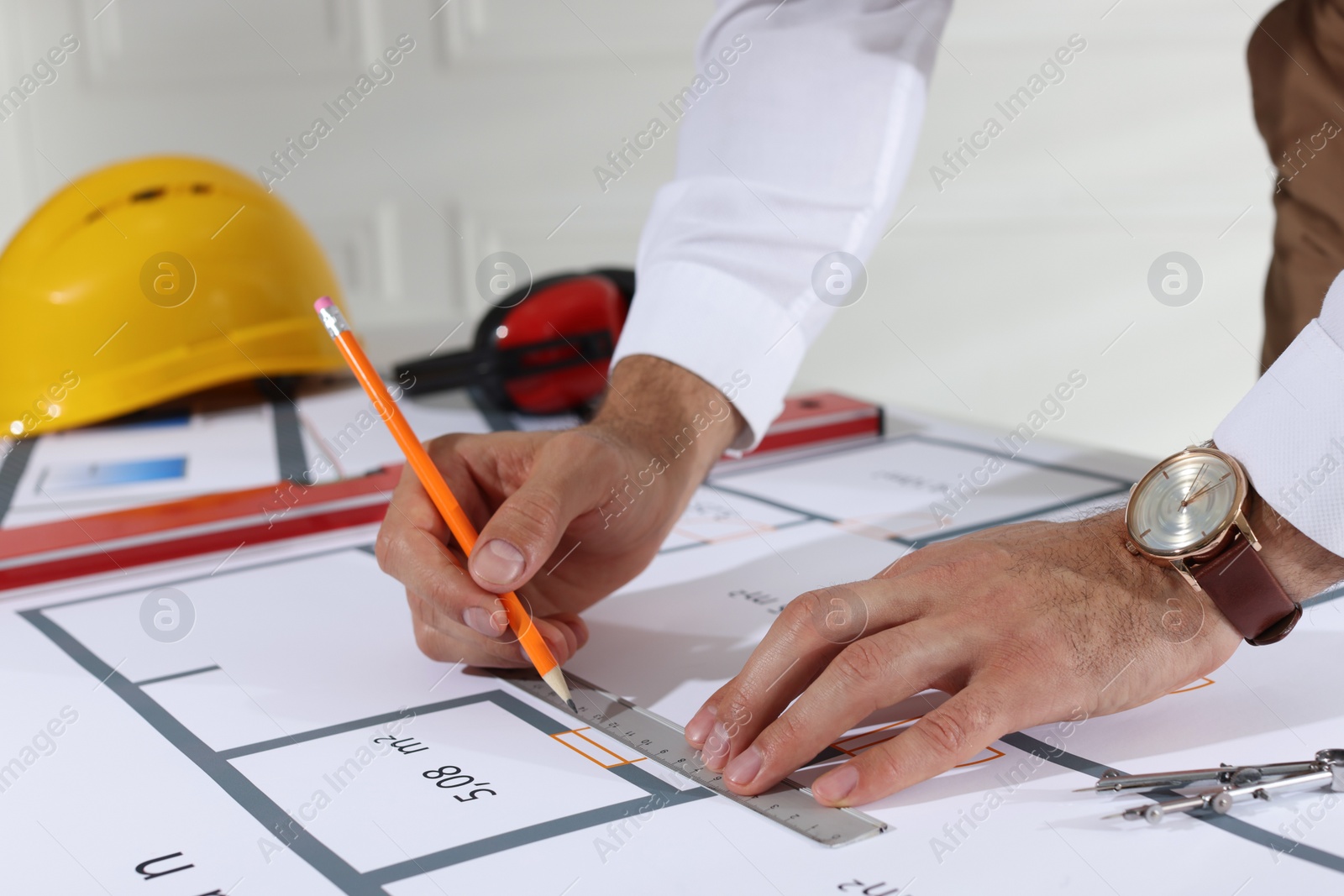 Photo of Architect working with construction drawings indoors, closeup