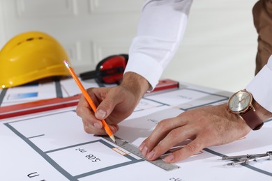 Photo of Architect working with construction drawings indoors, closeup