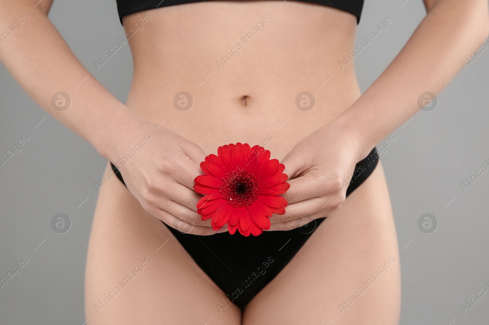 Photo of Gynecology. Woman in underwear with gerbera flower on grey background, closeup