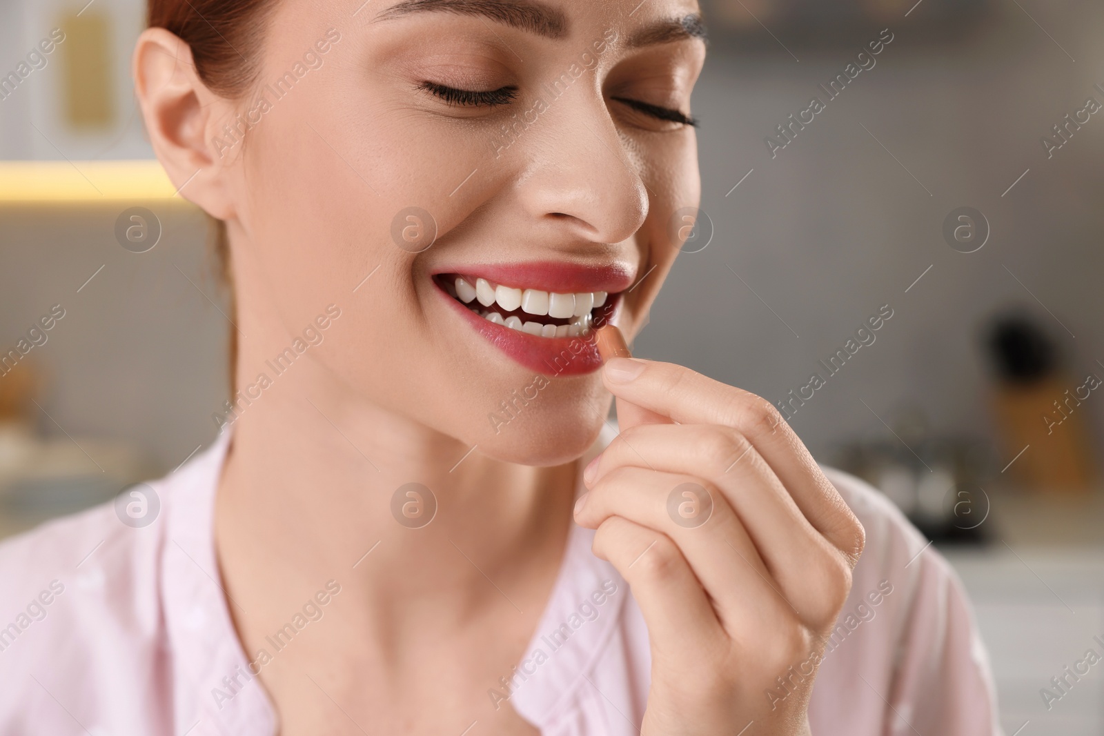 Photo of Beautiful young woman taking vitamin pill at home, closeup