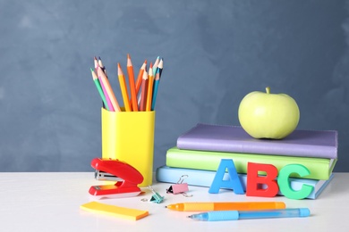 Apple and different school stationery on white wooden table