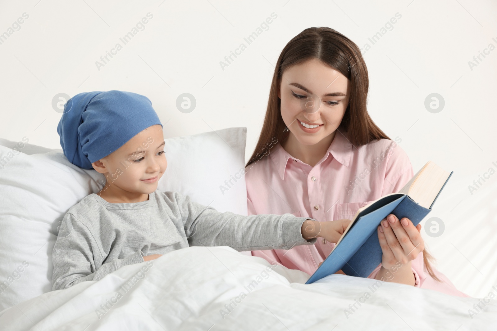 Photo of Childhood cancer. Mother and daughter reading book in hospital