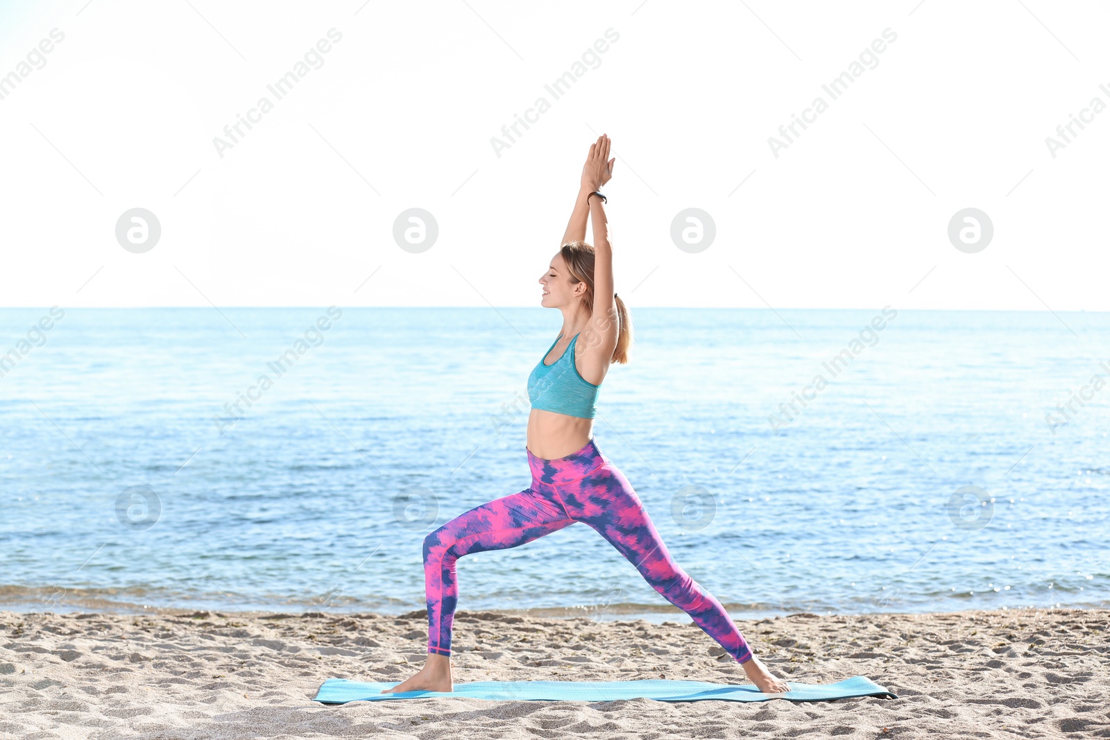Photo of Young woman doing yoga exercises on beach in morning