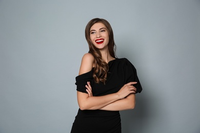 Happy woman in black dress on grey background. Christmas party