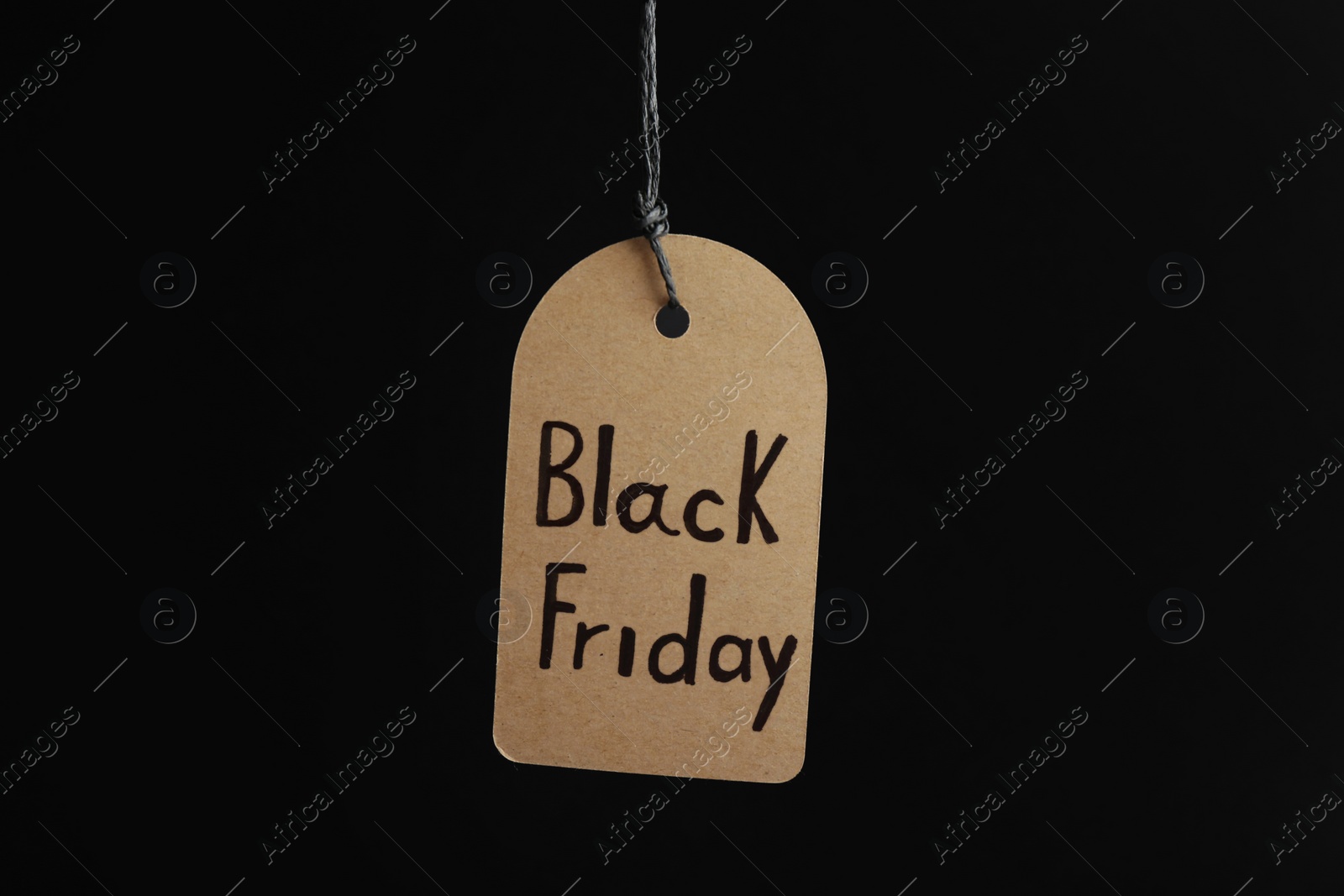 Photo of Tag with words BLACK FRIDAY hanging on dark background