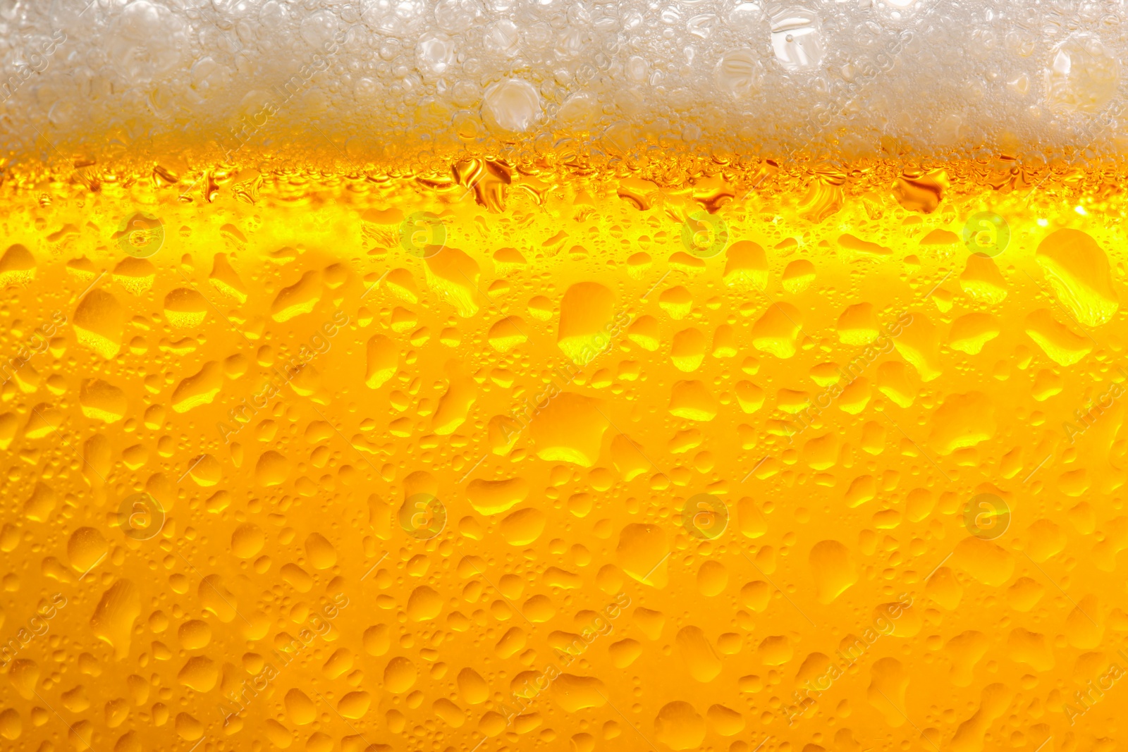 Photo of Glass of tasty cold beer with foam and condensation drops as background, closeup