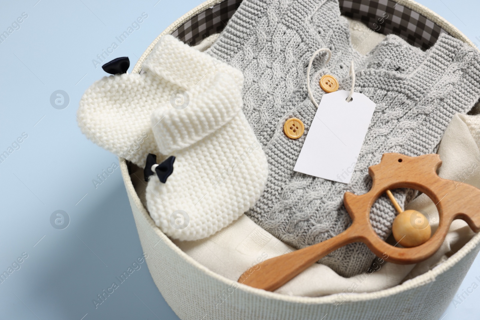Photo of Different baby accessories and clothes in box on light blue background, closeup