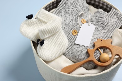 Different baby accessories and clothes in box on light blue background, closeup