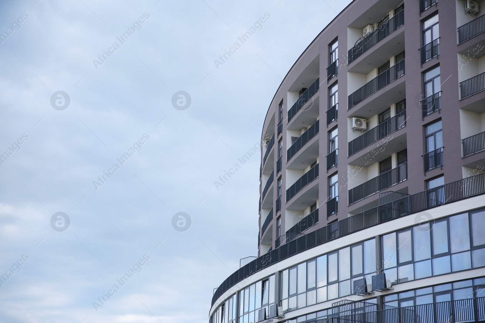 Photo of Modern building with big windows against blue sky outdoors, space for text