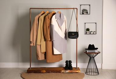 Photo of Different warm coats on rack in stylish room interior