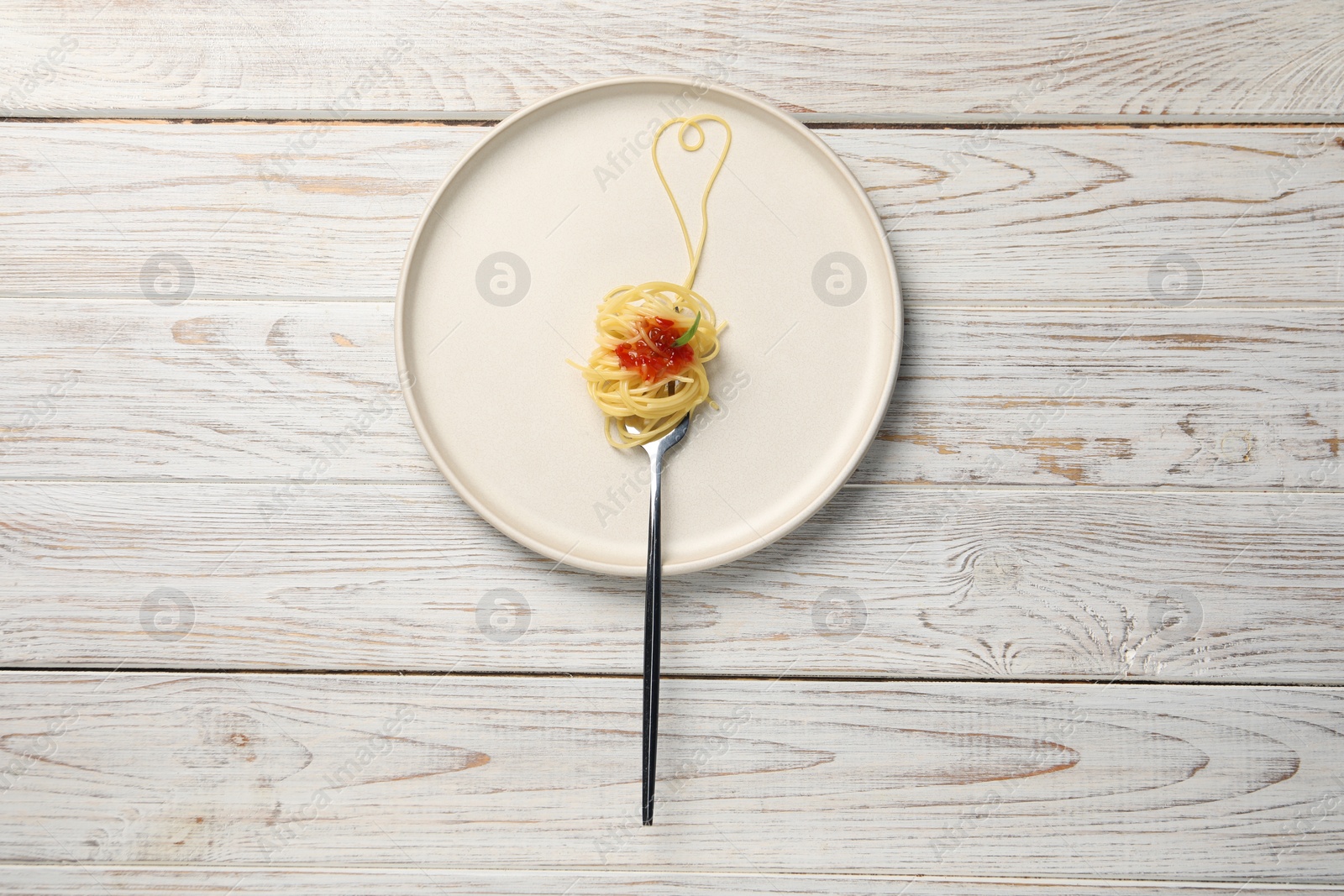 Photo of Heart made with spaghetti and fork on white wooden table, top view