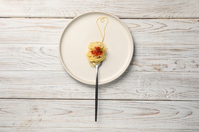 Photo of Heart made with spaghetti and fork on white wooden table, top view
