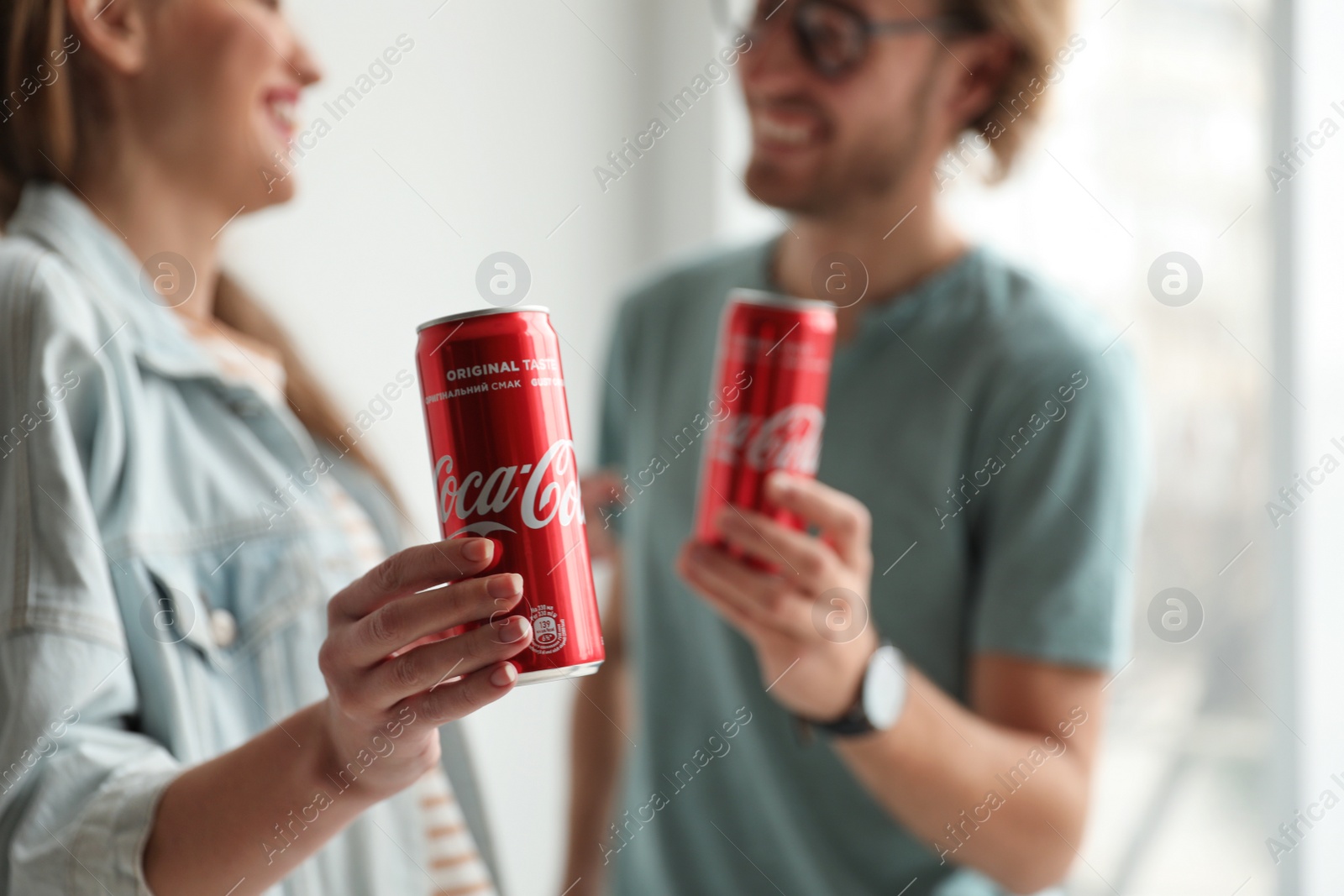 Photo of MYKOLAIV, UKRAINE - NOVEMBER 28, 2018: Young couple with Coca-Cola cans indoors