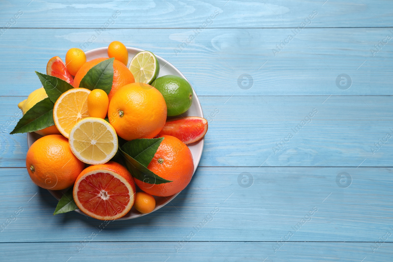 Photo of Different citrus fruits on light blue wooden table, top view. Space for text