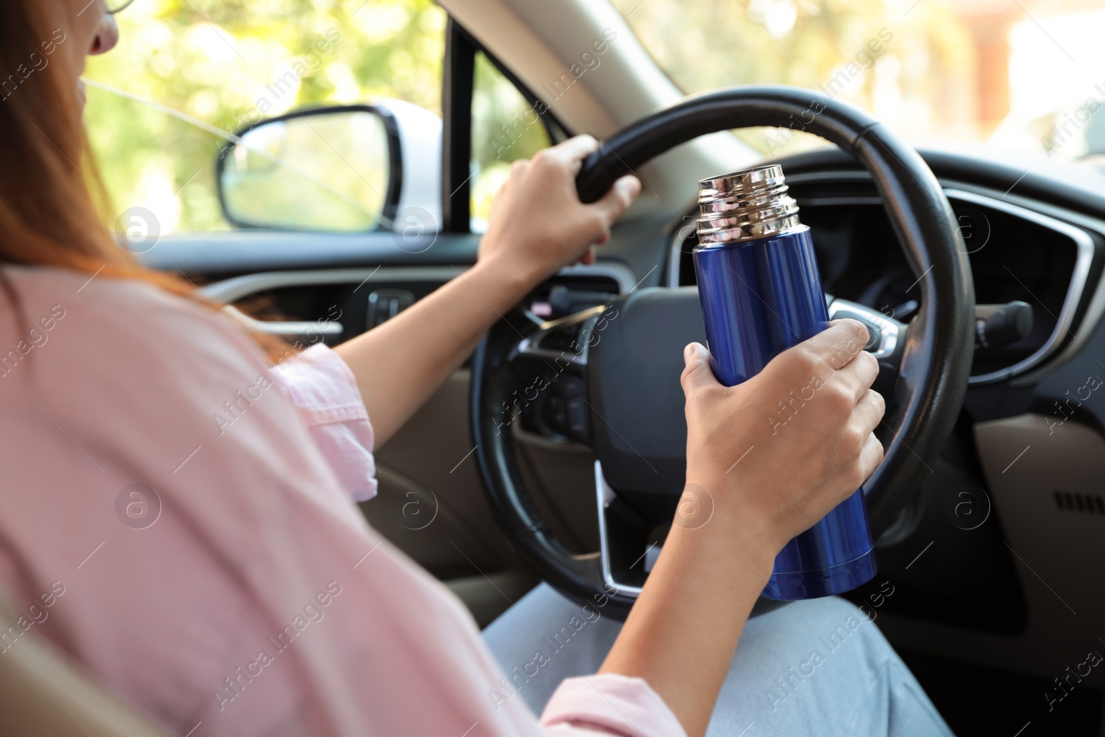 Photo of Woman with thermos driving car, closeup view