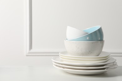 Photo of Stack of beautiful ceramic dishware on white table, space for text