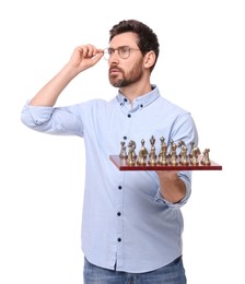Handsome man holding chessboard with game pieces on white background