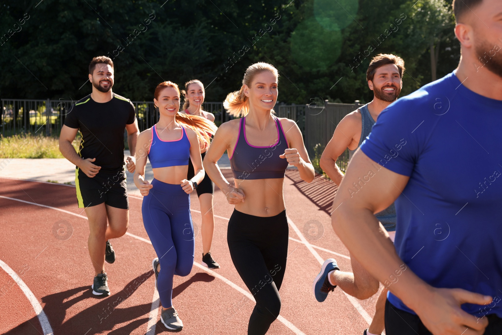 Photo of Group of people running at stadium on sunny day