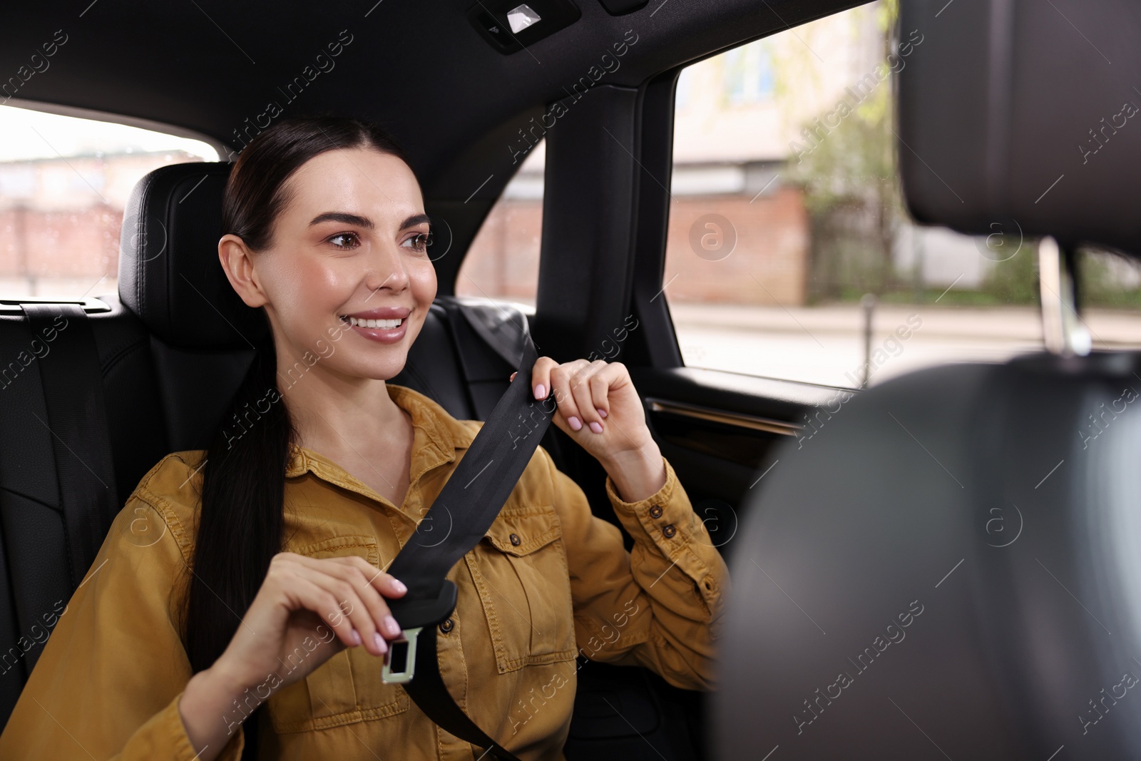 Photo of Woman fastening safety seat belt inside modern car