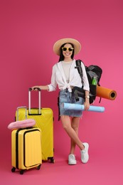 Female tourist with travel accessories on pink background