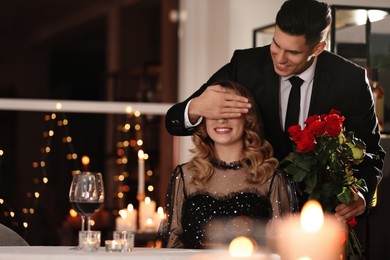 Photo of Man presenting roses to his beloved woman in restaurant at Valentine's day dinner