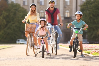 Photo of Happy family riding bicycles outdoors on summer day