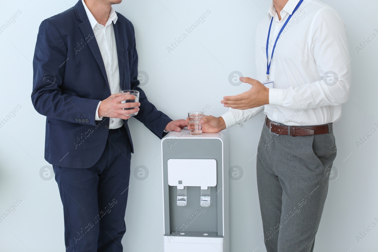 Photo of Men having break near water cooler on white background, closeup