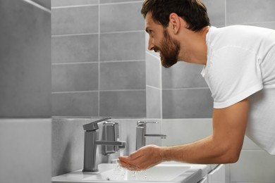 Photo of Handsome man washing hands in stylish bathroom