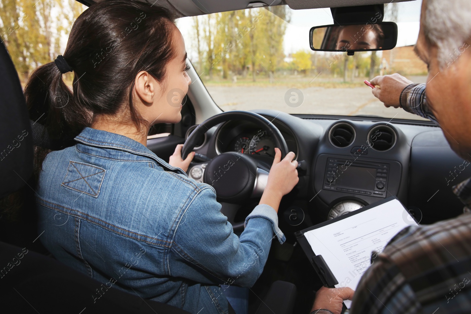 Photo of Young woman and senior instructor in car. Passing driving license exam