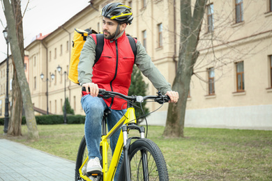 Courier with thermo bag riding bicycle outdoors. Food delivery service