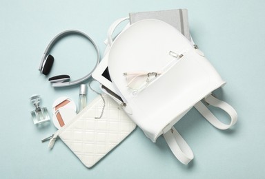 Photo of Stylish urban backpack with different items on light background, flat lay