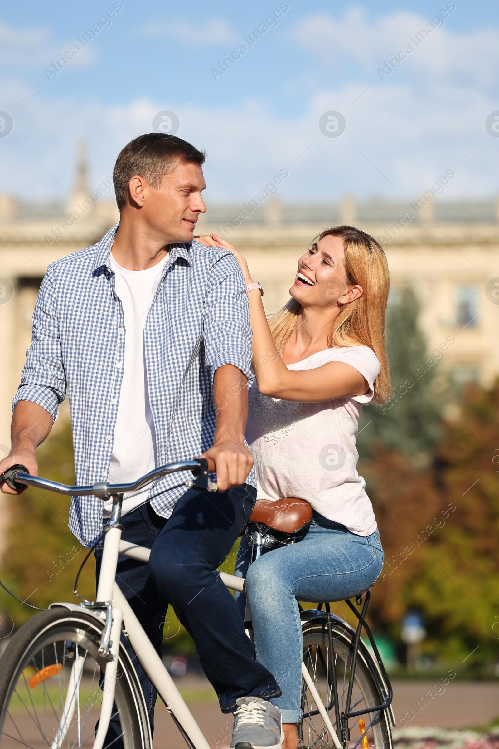 Photo of Happy couple riding bicycle outdoors on sunny day