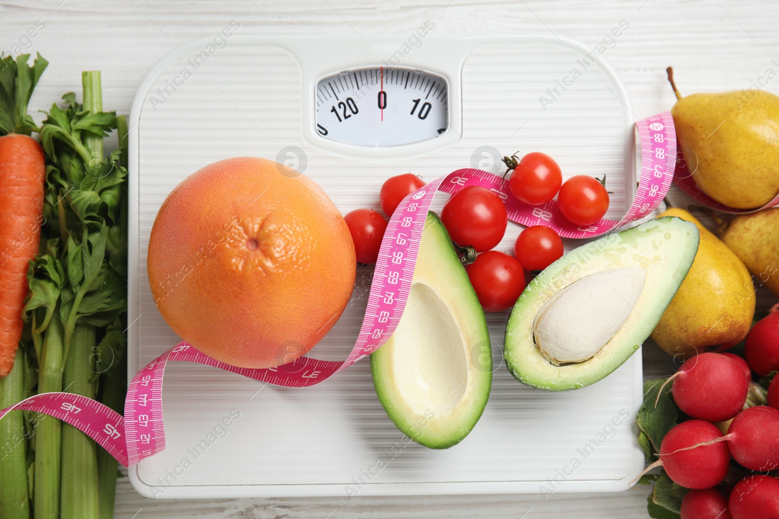 Flat lay composition with scales and healthy food on white wooden table Photo of Flat lay composition with scales and healthy food on white wooden table