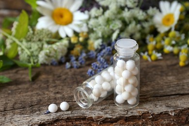 Photo of Bottles with homeopathic remedy and flowers on wooden table