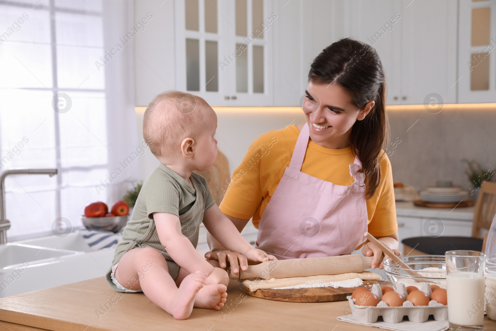 Photo of Happy young woman and her cute baby cooking together in kitchen