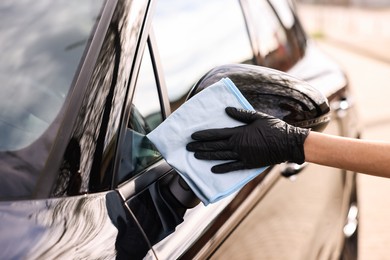 Photo of Woman wiping her modern car with rag, closeup