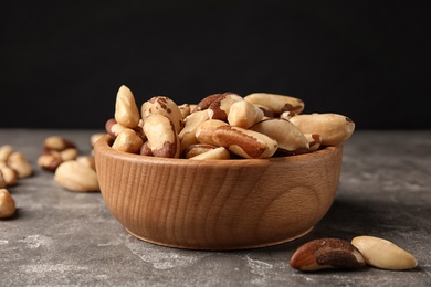 Bowl with tasty Brazil nuts on grey table