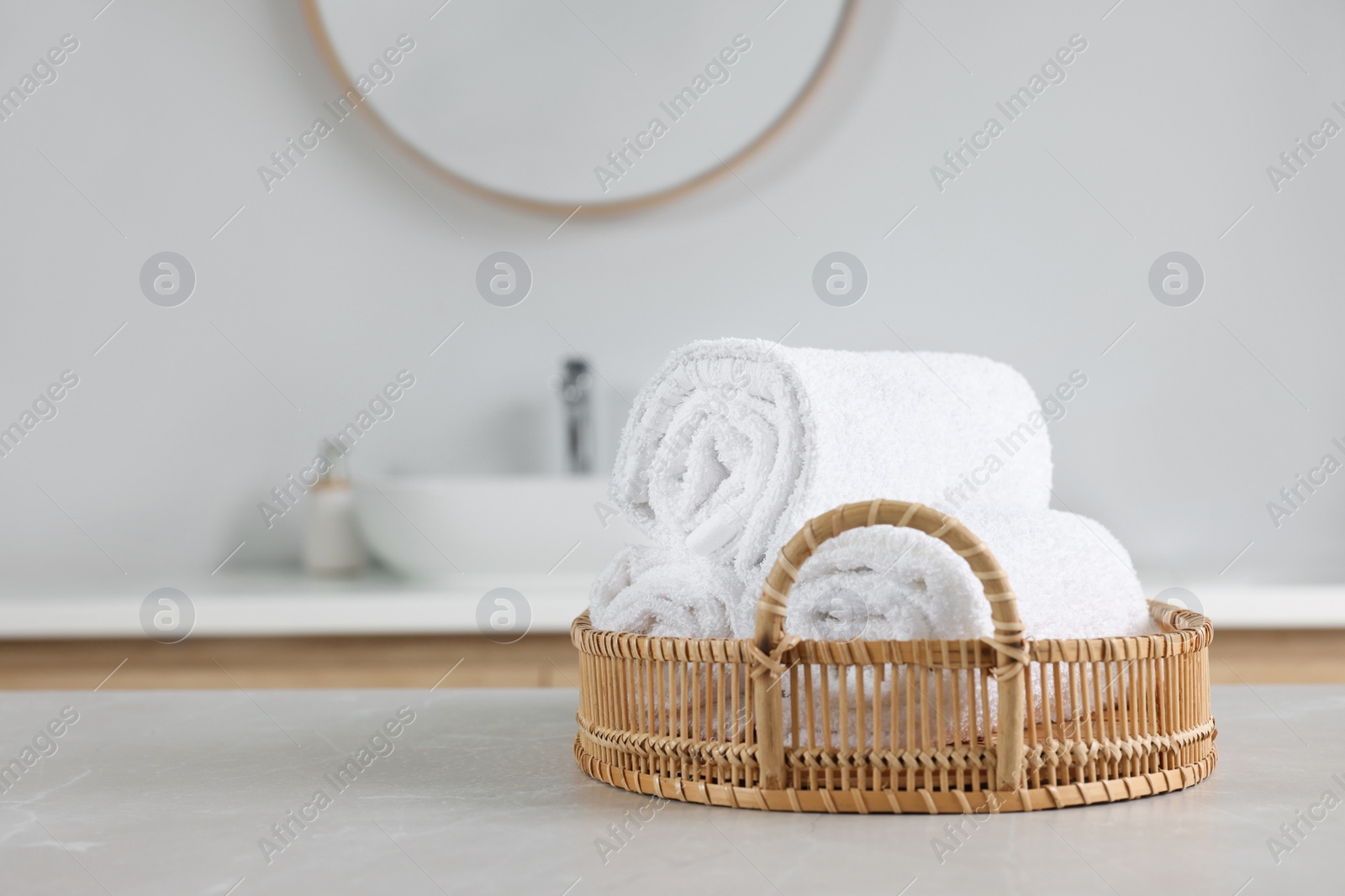 Photo of Wicker basket with white towels on table in bathroom. Space for text