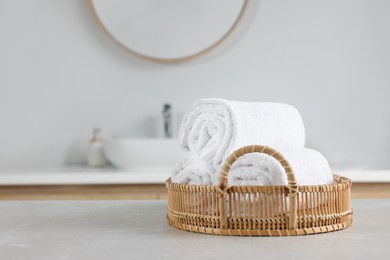 Photo of Wicker basket with white towels on table in bathroom. Space for text