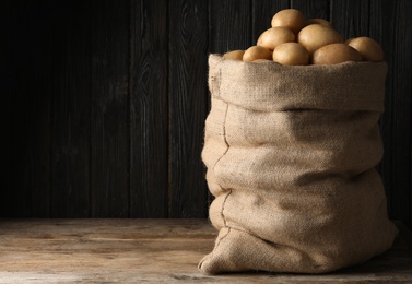 Raw fresh organic potatoes on wooden table against dark background. Space for text