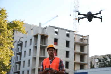 Builder operating drone with remote control at construction site. Aerial survey